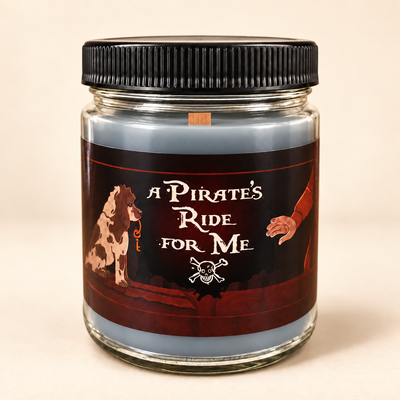A glass jar candle with a black ribbed screw-on lid and a pirate-themed label reading 'A PIRATE'S RIDE FOR ME,' featuring a dog, a hand, and a skull-and-crossbones motif on a warm beige background.
