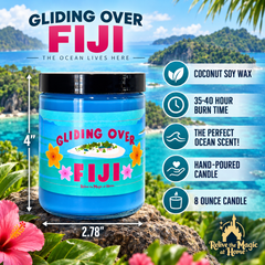 An 8-ounce scented candle jar labeled 'Gliding Over Fiji' with tropical beach scenery in the background and product feature callouts on the right. The candle jar is blue with a black lid and a colorful label showing a small island and flowers.